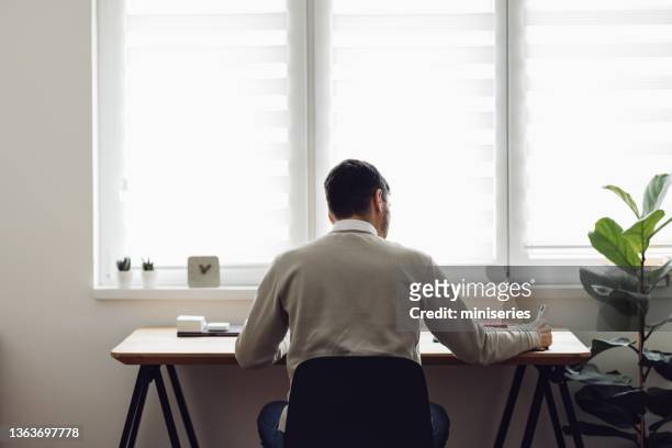 home office: man sitting at the table and writing - student journalist stock pictures, royalty-free photos & images