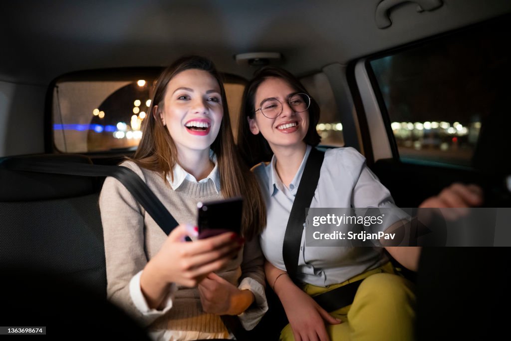 Young women having fun while driving in the taxi