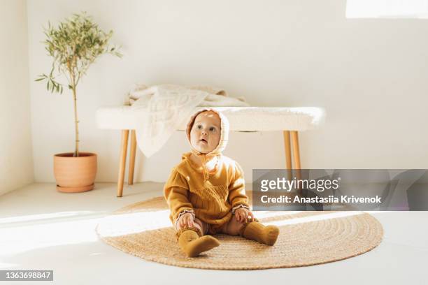 adorable beautiful six month old baby girl sitting on wicker carpet at living room. - beautiful living room stock-fotos und bilder