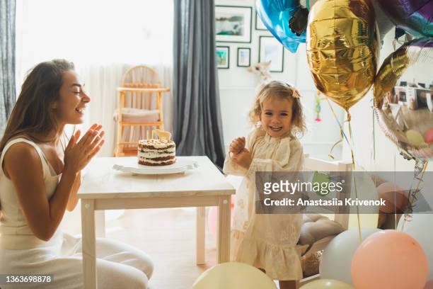 young girl with his mother blowing candles for celebreating her 2th years birthday. - 2 3 years stock-fotos und bilder