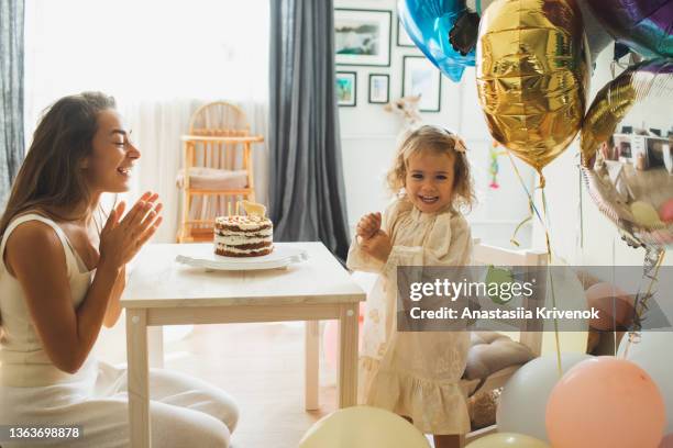 young girl with his mother blowing candles for celebreating her 2th years birthday. - 2 3 years foto e immagini stock