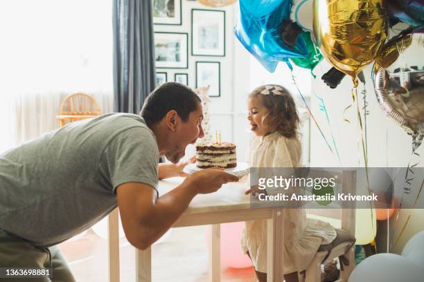 young girl with father eating cake and having fun for celebreating her 2th years birthday. - 2 3 years stock-fotos und bilder
