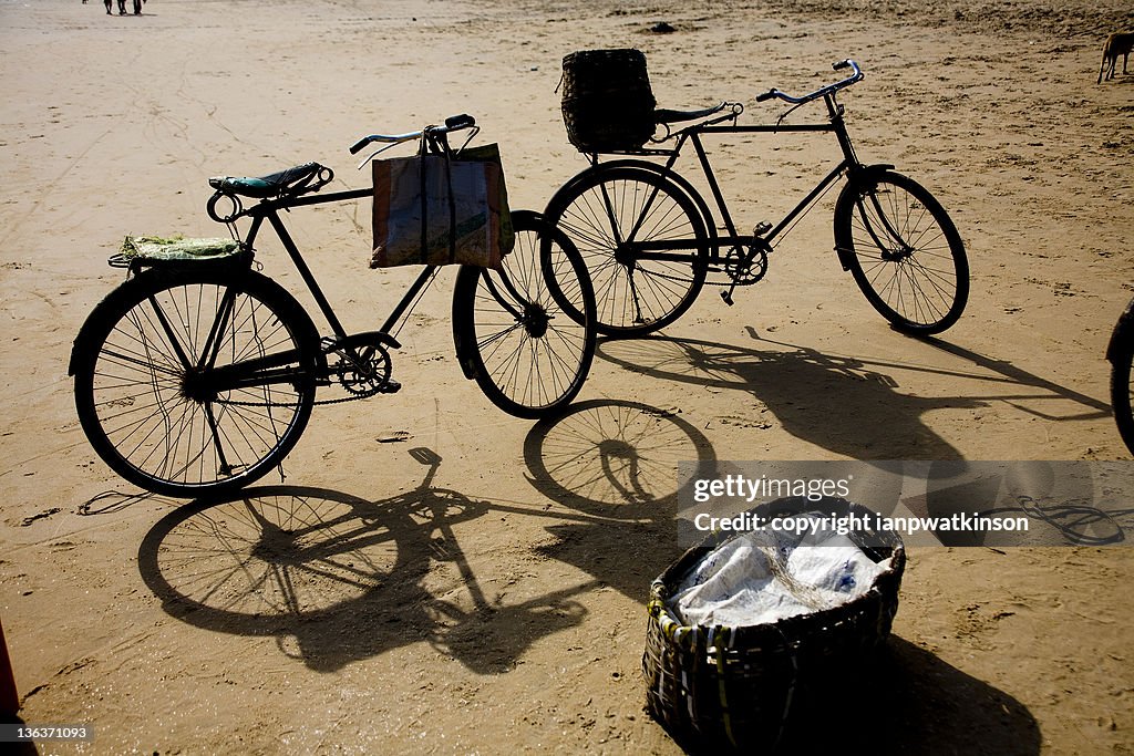 Two bicycles with carry bags beside fish basket