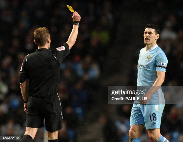Manchester City's English footballer Gareth Barry is shown the yellow card by the referee as he plays against Liverpool during their english Premier...