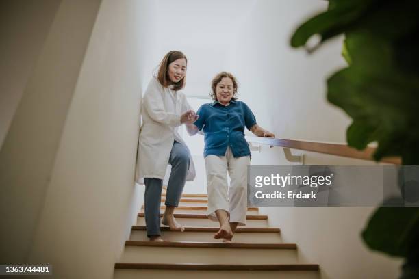senior and her doctor while walking down stairs-stock photo - open workout stockfoto's en -beelden