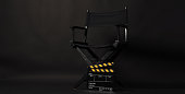 Black Director chair with black and yellow Clapper board or movie slate isolated on black background.
