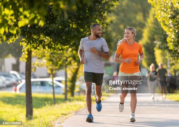 mann und frau laufen im öffentlichen park - jogging park stock-fotos und bilder
