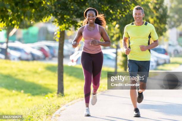 mann und frau laufen im öffentlichen park. - purple pants stock-fotos und bilder