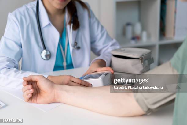faceless doctor measuring blood pressure with tonometer. cardiologist checking heartbeat and pulse - artery fotografías e imágenes de stock