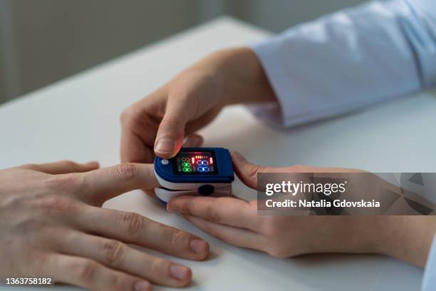 monitoring oxygen level on electronic oximeter. faceless doctor measuring saturation of patient - puls oxymeter stock-fotos und bilder