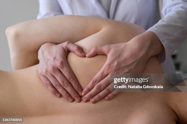 closeup of osteopathic masseur massages patient back, relieving tension from muscles and toning up - chiropractic stock-fotos und bilder