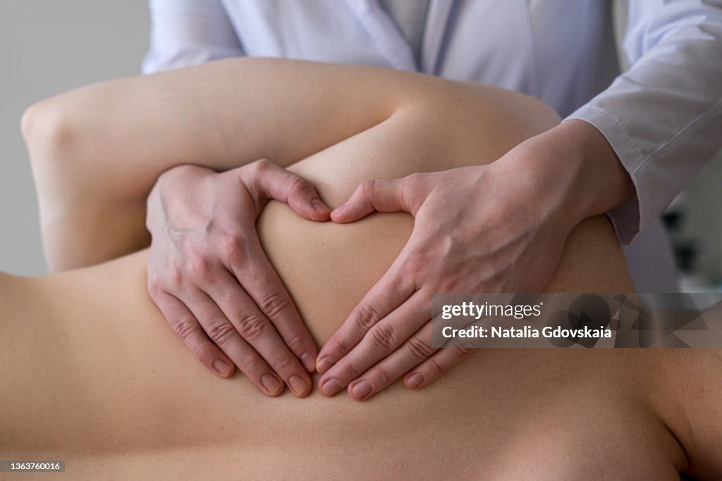 Closeup of osteopathic masseur massages patient back, relieving tension from muscles and toning up
