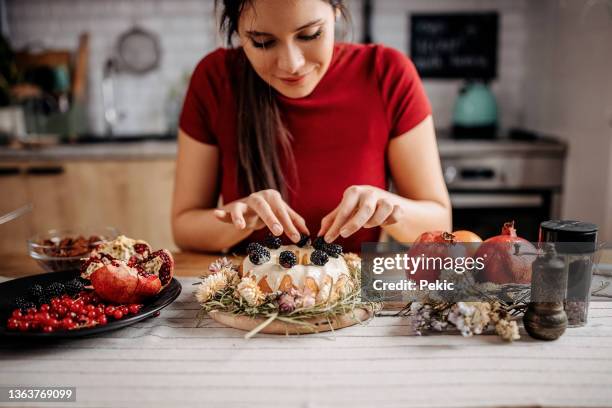 young beautiful woman decorating her cake with berry fruits - decorar um bolo imagens e fotografias de stock
