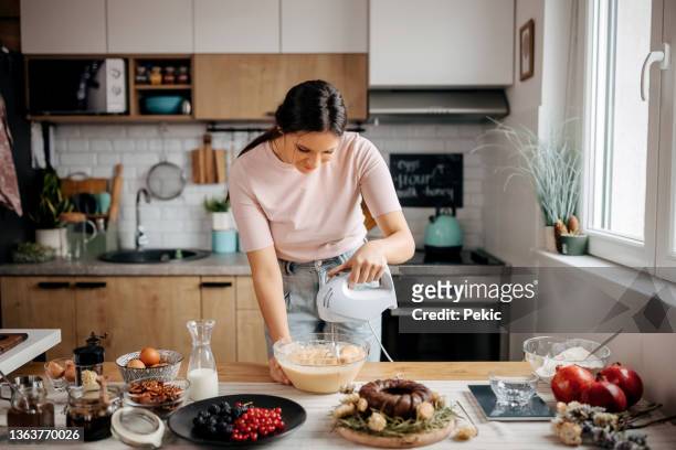 young beautiful woman making a cake mixture - cake stockfoto's en -beelden