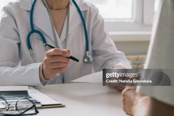 unrecognizable doctor consulting patient. giving piece of paper with instructions and recommendations - medico di famiglia foto e immagini stock