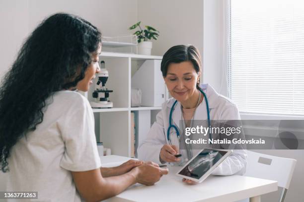 mature female doctor discussing mri results with afro american woman in clinic office - 女性患者 ストックフォトと画像