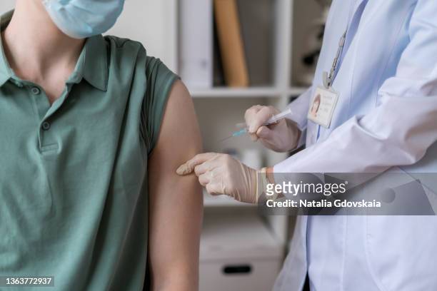anonymous doctor making to male patient covid19 vaccine in arm, effective injection in clinic office - smallpox epidemic stock pictures, royalty-free photos & images