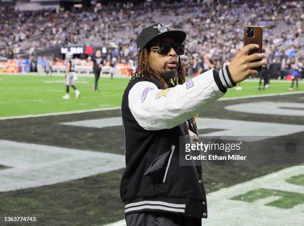 Rapper Lil Jon records images on the field with a cell phone before a game between the Los Angeles Chargers and the Las Vegas Raiders at Allegiant...