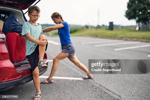 kinder, die sich während des roadtrip-stopps dehnen - autostop stock-fotos und bilder