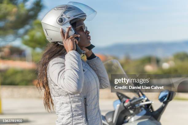 female motorcyclist in her forties strapping on her helmet. - adjusting ストックフォトと画像