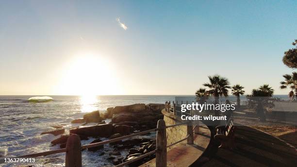 woman walking on boardwalk promenade sea point cape town at sunset over the atlantic ocean - sea point cape town stock pictures, royalty-free photos & images