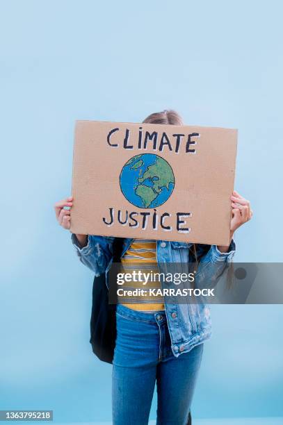 little girl is holding a cardboard sign that says climate justice. - female activist stock pictures, royalty-free photos & images