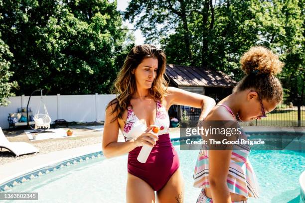 mother putting sunscreen on daughter before swimming in pool - putting lotion stock pictures, royalty-free photos & images