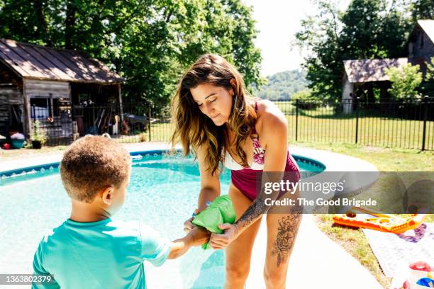 mother helping son put on water wings b - arm floats stock pictures, royalty-free photos & images