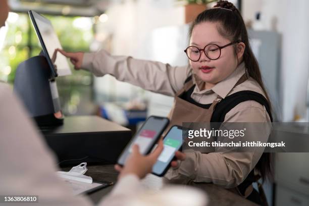 asian teenage girl down syndrome contactless payment in coffee shop. - disabilitycollection fotografías e imágenes de stock