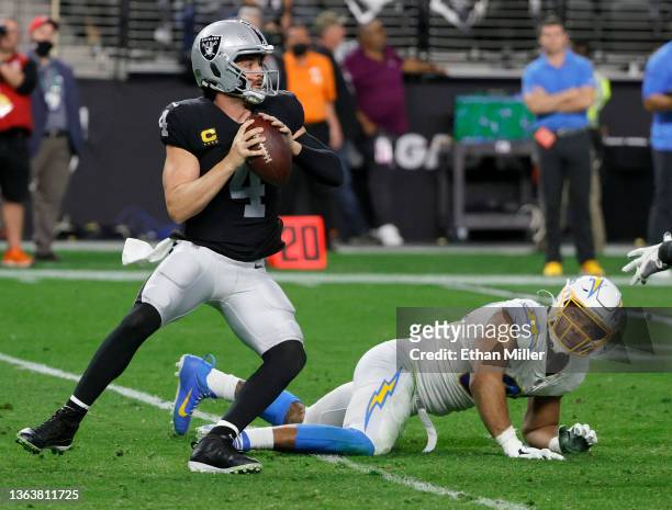 Quarterback Derek Carr of the Las Vegas Raiders looks to pass as he avoids a sack by defensive end Jerry Tillery of the Los Angeles Chargers during...