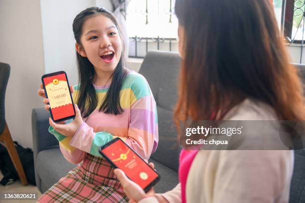 asiatisches mädchen zeigt ihren digitalen chinesischen neujahrs-e-roten umschlag auf smartphone übertragen - chinese new year red envelope stock-fotos und bilder