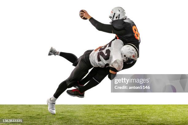 two american football players in action, motion. sportsmen fight for ball isolated on white background on grass - shooting football stock pictures, royalty-free photos & images