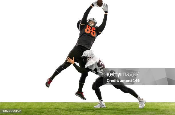 two american football players in action, motion. sportsmen fight for ball isolated on white background on grass - receiver imagens e fotografias de stock