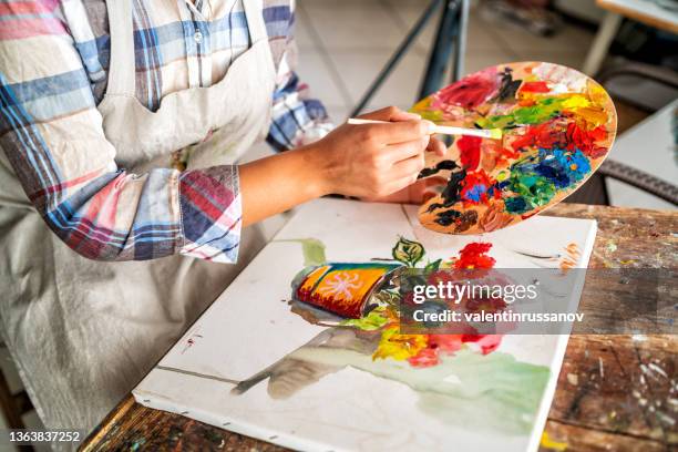 close up on an afro female fine artist's painting. fine artist holding palette and a paintbrush and drawing on a canvas. - artist palette stock pictures, royalty-free photos & images