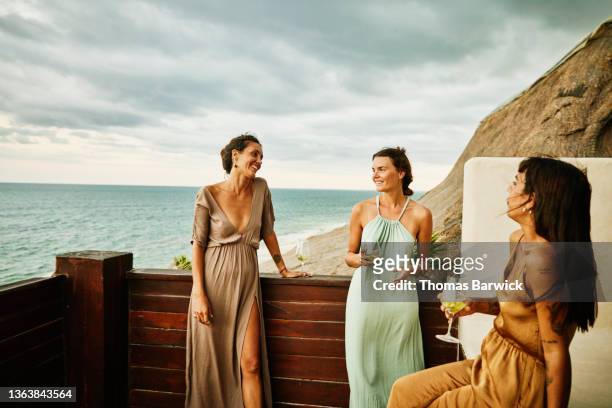 medium wide shot of smiling and laughing female friends hanging out on deck of luxury hotel suite - medium group of people foto e immagini stock
