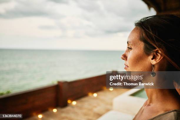 medium close up portrait of woman watching sunset from deck of luxury hotel suite - mid volwassen vrouw stockfoto's en -beelden