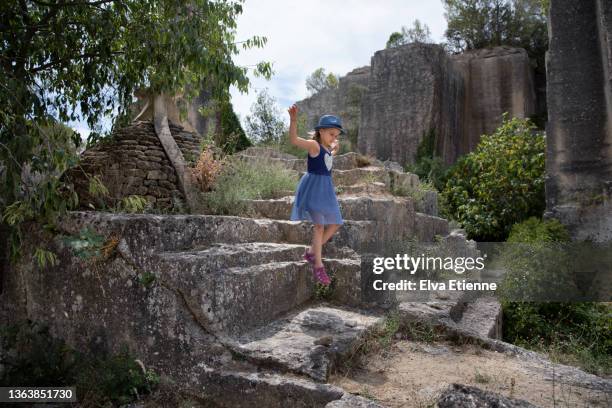 child (8-9) jumping off stone steps carved into rock at an old quarry in summertime - gard photos et images de collection
