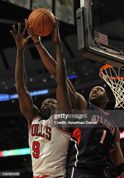 Loul Deng of the Chicago Bulls grabs a rebound away from Tracy McGrady of the Atlanta Hawks at the United Center on January 3, 2012 in Chicago,...