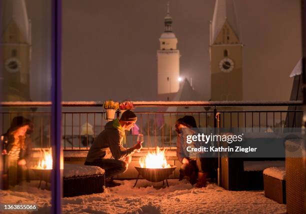 couple enjoying the warmth by fire pit on snowy terrace - paradise fire stock pictures, royalty-free photos & images