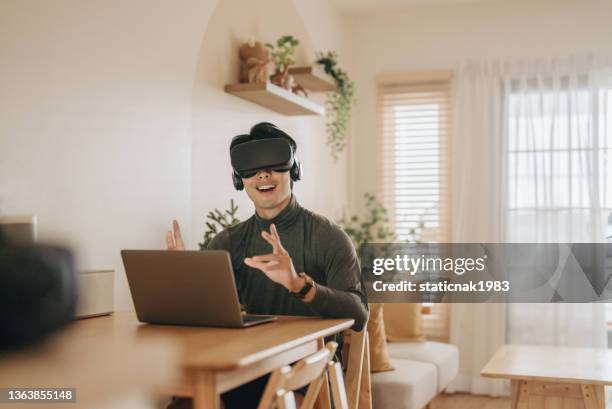 hombre asiático trabaja desde casa con gafas de realidad virtual en casa. - mirar alrededor fotografías e imágenes de stock