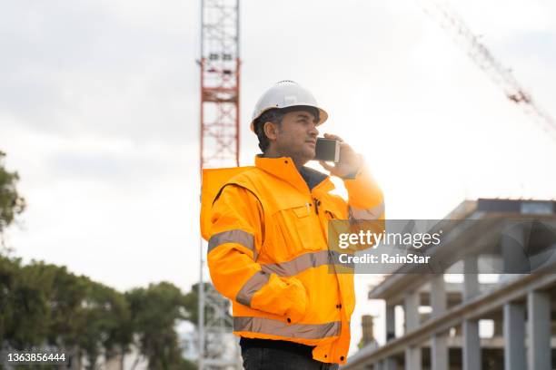 engineer talking by phone at construction site - smartphones dangling stock pictures, royalty-free photos & images