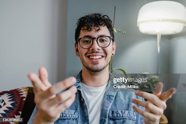 junger mann spricht bei einem videoanruf und schaut in die kamera - video call stock-fotos und bilder