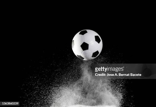 impact and rebound of a soccer ball on a surface of earth and gunpowder on a black background - ballon rebond stock pictures, royalty-free photos & images