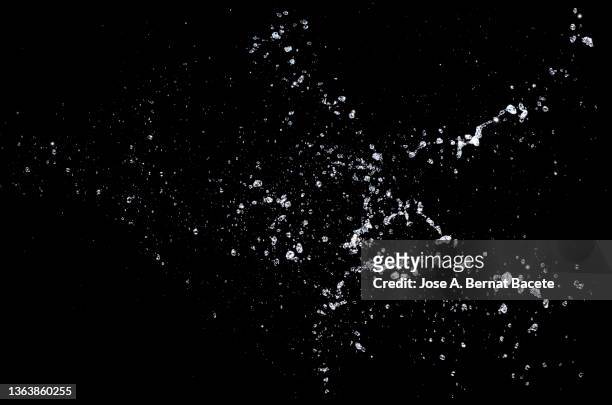 drops and splashes of water floating in the air on a black background. - bubble popping stock pictures, royalty-free photos & images