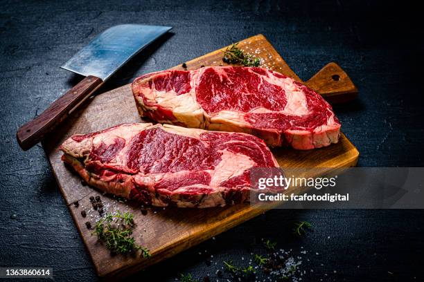 raw juicy beef steak fillets on black table - köttyxa bildbanksfoton och bilder