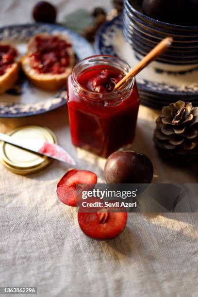 engelhafte pflaumenmarmelade in einem kleinen sechseckigen glas auf einer beigen leinentischdecke - marmelade stock-fotos und bilder