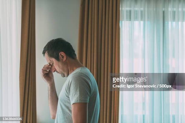 depressed man standing by the window at home,serbia - medelålderskris bildbanksfoton och bilder