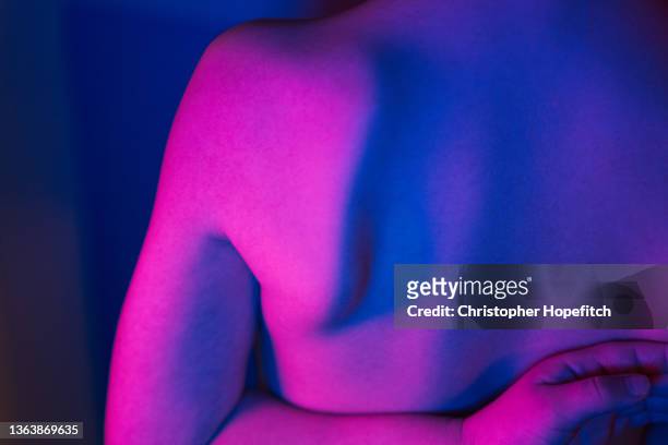 close up of a young boy's back lit with neon colours - escapula fotografías e imágenes de stock