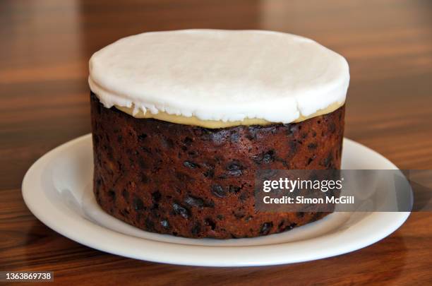 moist christmas fruit cake topped with marzipan and plain white royal icing - fruitcake stock-fotos und bilder