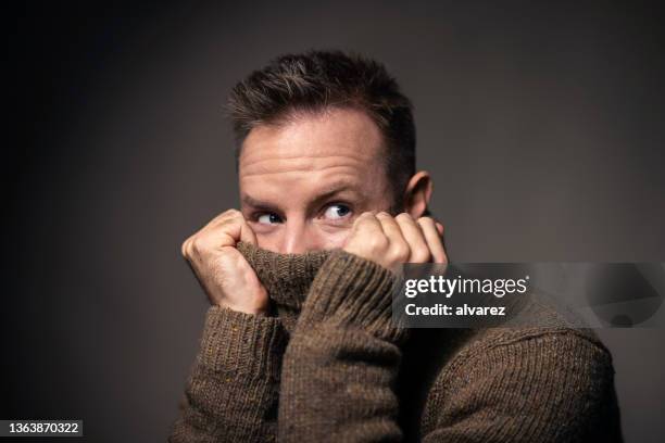 young man covering face with turtleneck sweater - awkward stock pictures, royalty-free photos & images